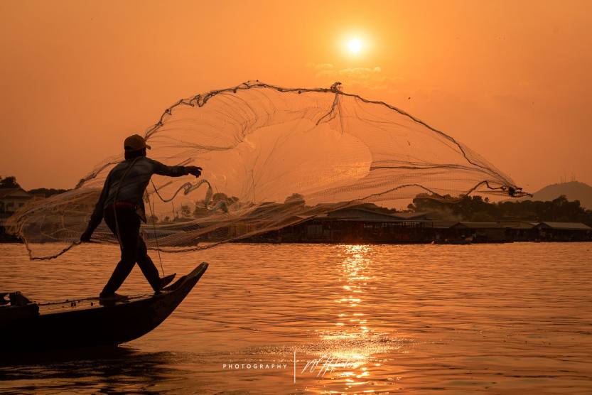 Man throws fishing net in floating village_ Kompong